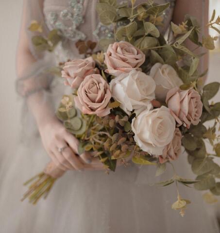 Bridal bouquet held in front of a gown